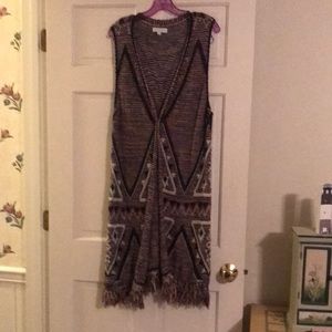 Duster length sweater vest with fringe trim
